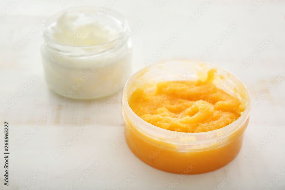 Jar with orange body scrub on light table