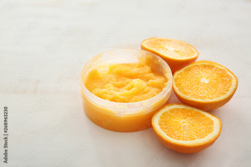 Jar with orange body scrub on light table