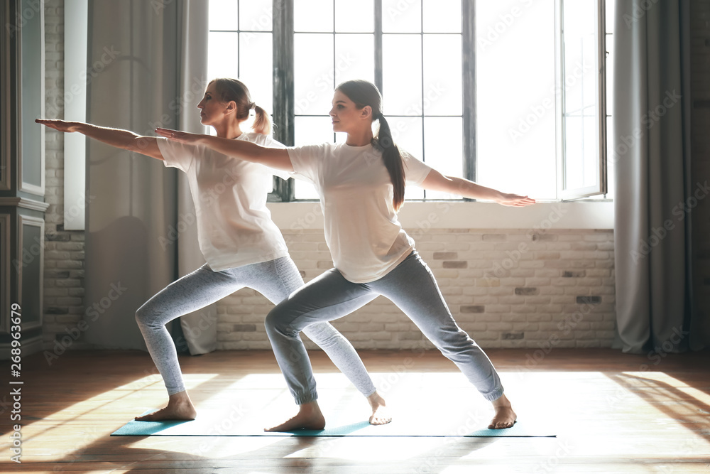 Young woman with her mother doing yoga at home