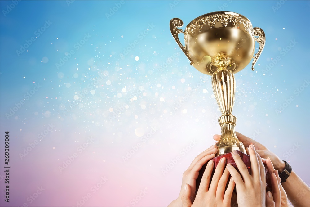 Hands holding golden trophy on light background