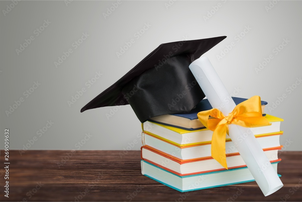 Graduation mortarboard on top of stack of books on  background