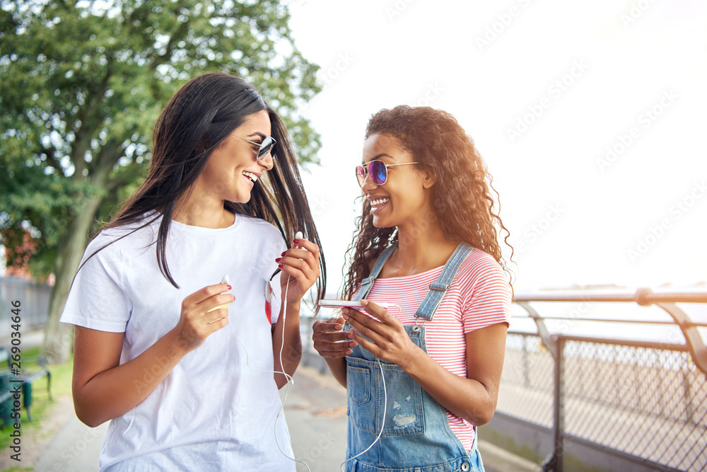 微笑的年轻女友一起走在外面听音乐