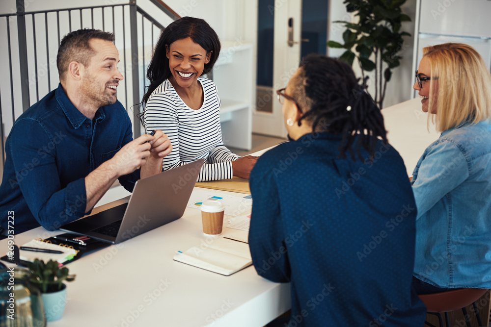 Smiling coworkers talking together at a table in an office