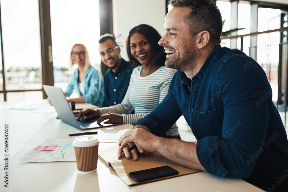 Businessman laughing with colleagues during an office meeting