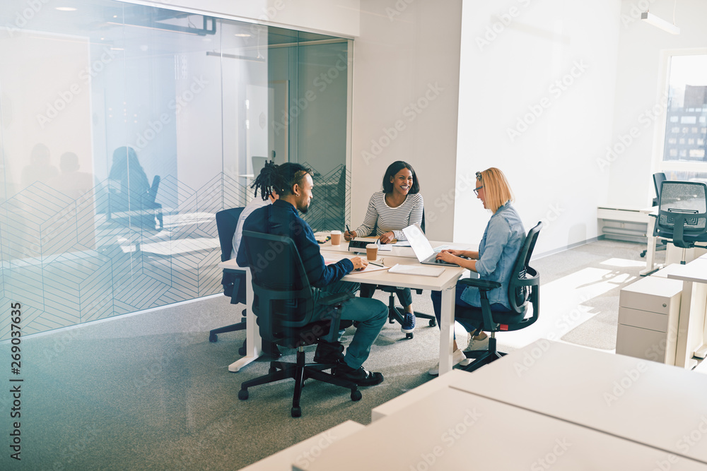 Group of work colleagues laughing during an office meeting toget