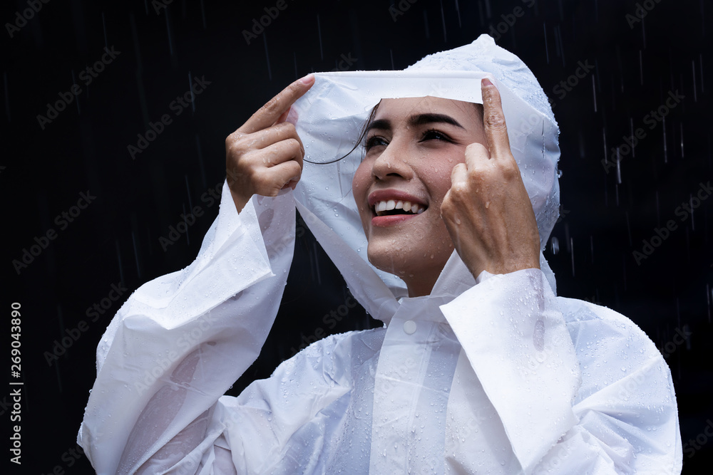 雨天亚洲女人在户外穿着雨衣。她很开心。