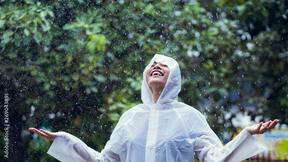 雨天亚洲女人在户外穿着雨衣。她很开心。