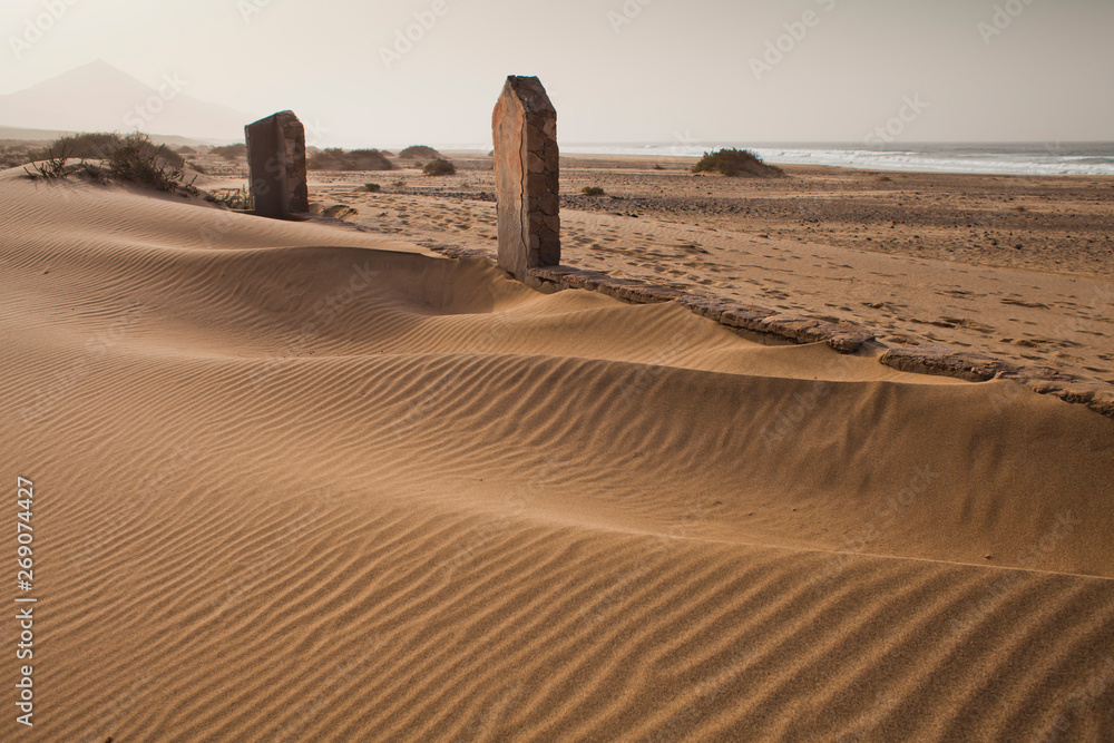 Сhristian Graveyard with abondend cemetery gate on sand dunes at Cofete beach during sunset, Fuertev