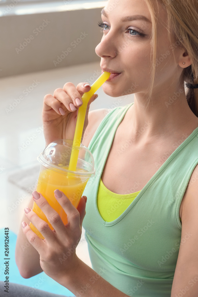 Sporty young woman drinking fresh juice at home