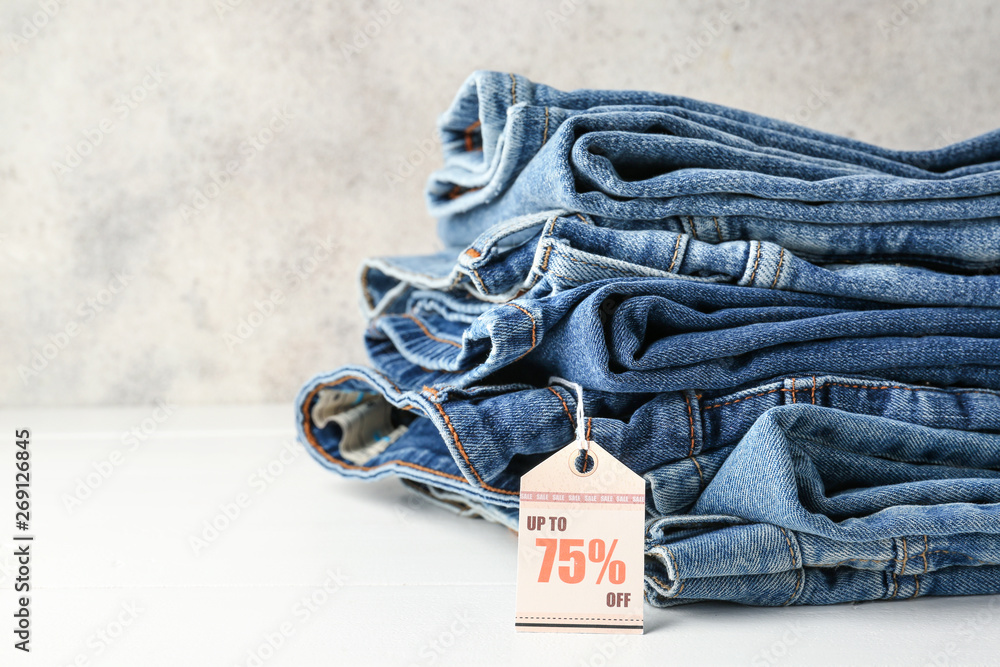 Stack of jeans clothes with tag on table