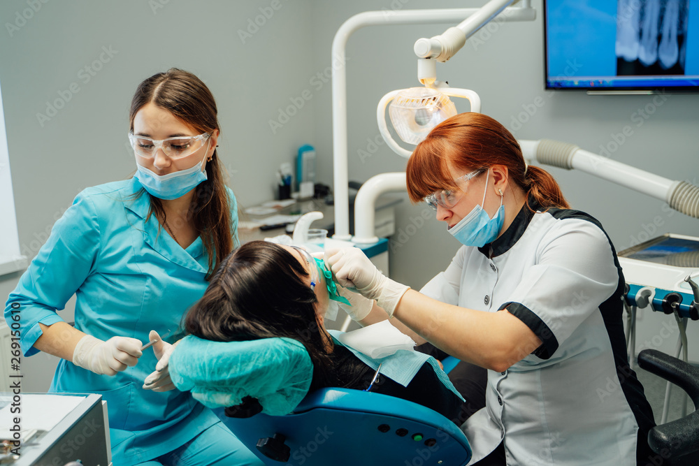 Stomatologist woman and her female assistant are working with a patient in medical clinic. Dentist a