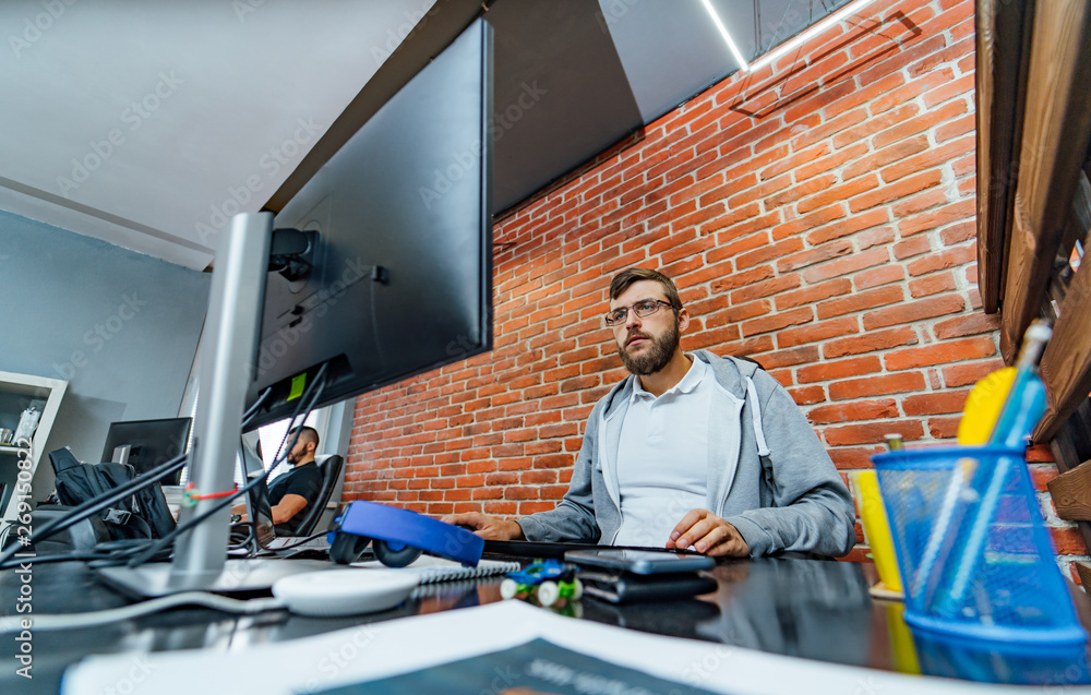 Bearded male computer programmer in glasses develops new technologies at his workplace. Creative emp