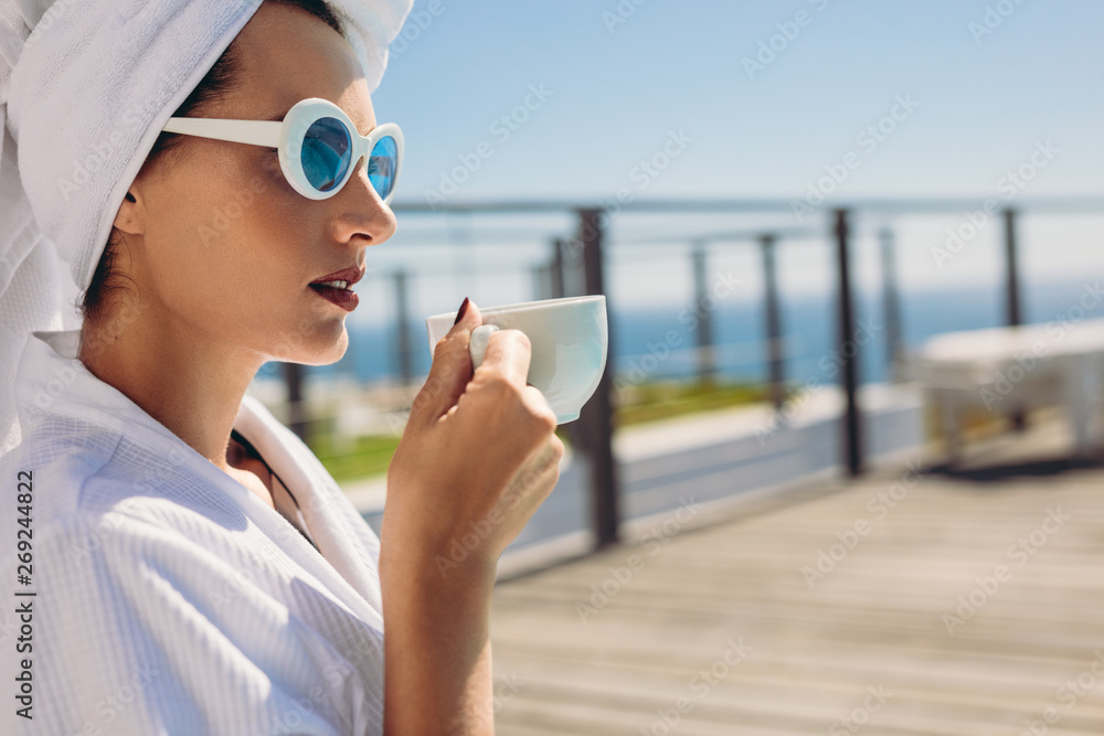 Woman sitting by pool having coffee