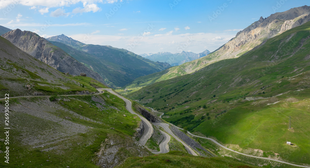 风景优美的蜿蜒道路蜿蜒在令人惊叹的法国阿尔卑斯山上长满青草的山丘上。