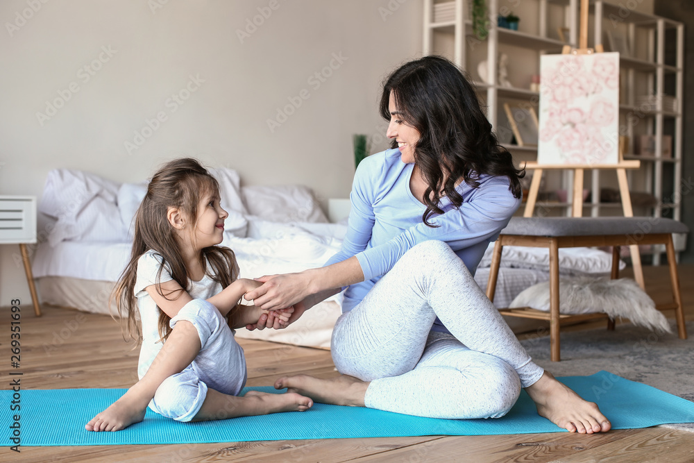 Mother with little daughter doing exercises at home