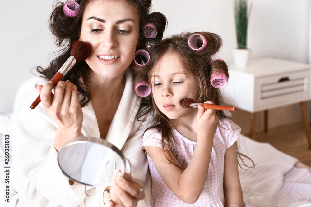 Mother with cute daughter doing makeup at home