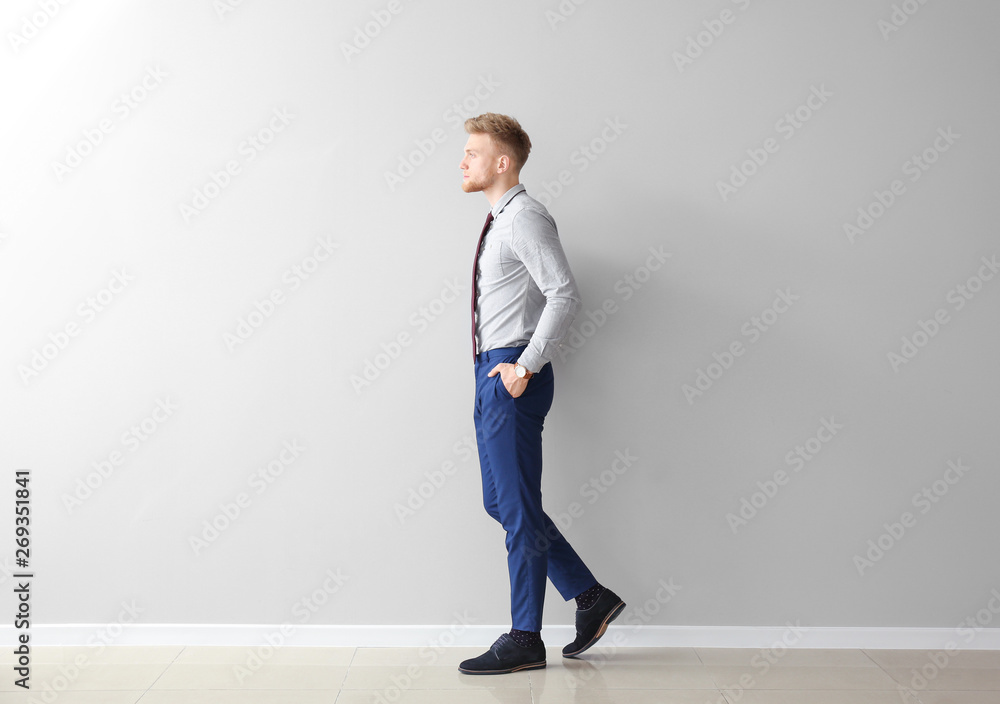 Fashionable young man near grey wall