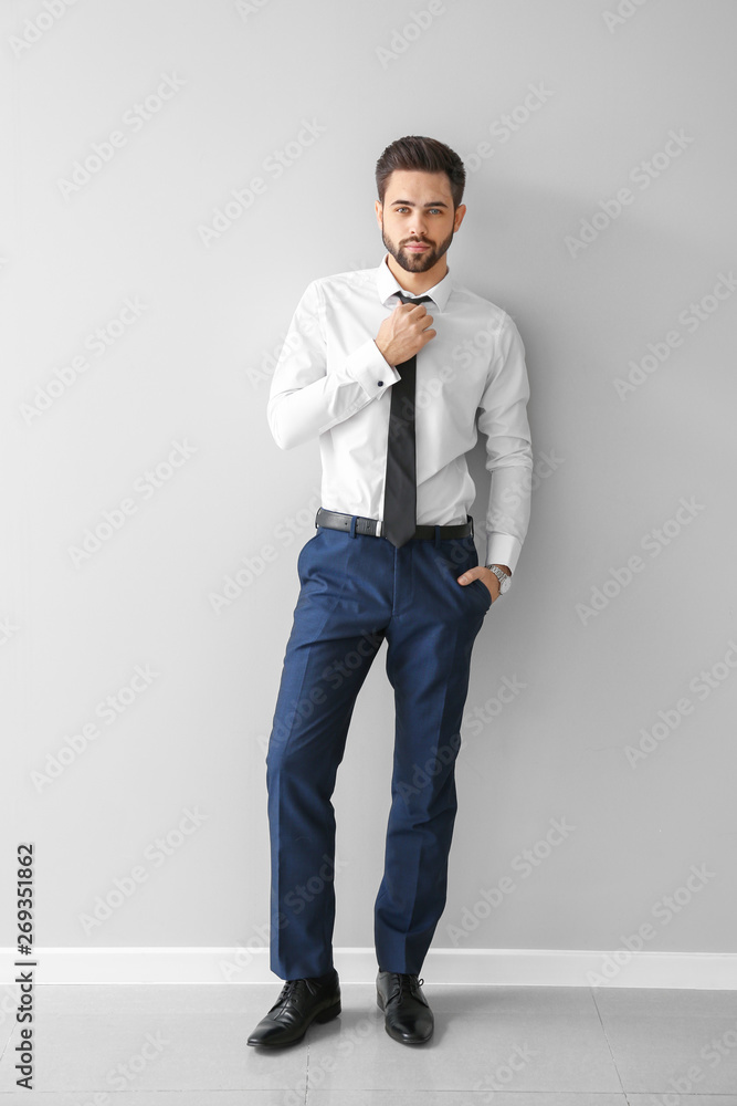 Fashionable young man near grey wall