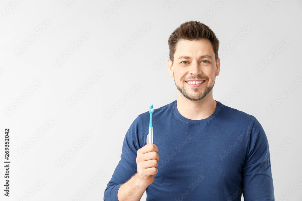 Man with toothbrush on light background