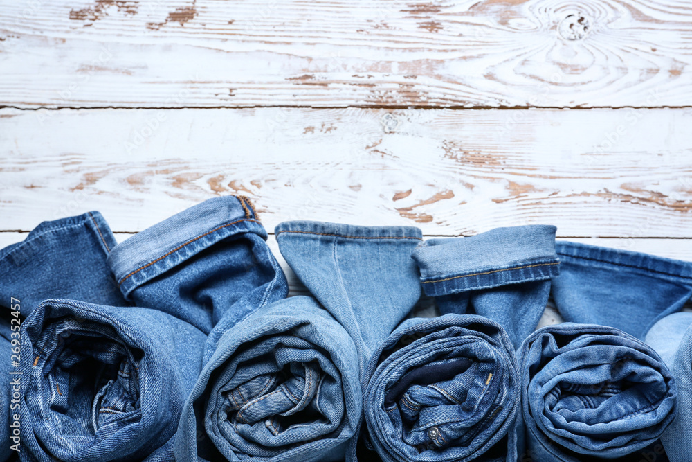 Different jeans pants on white wooden background