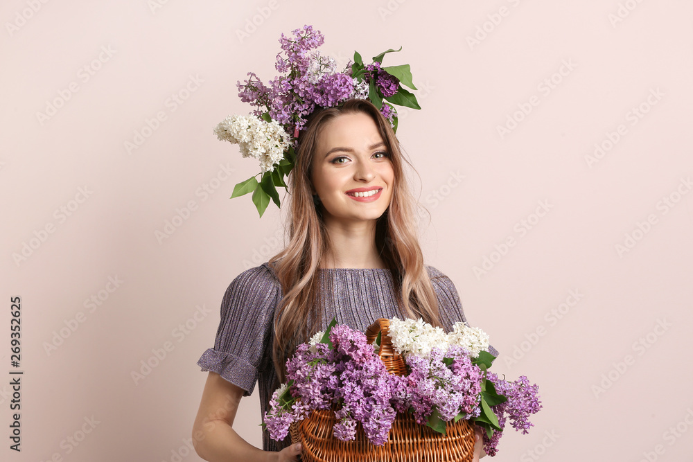 Beautiful young woman with lilac flowers on light background