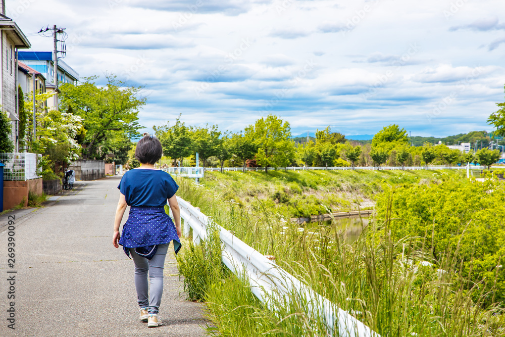 川沿いの遊歩道をウォーキングする女性