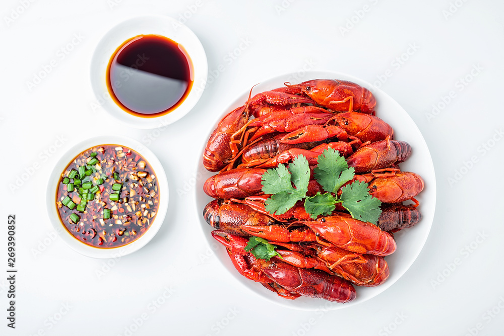 Delicious boiled crayfish and sauce on a saucer on a white background