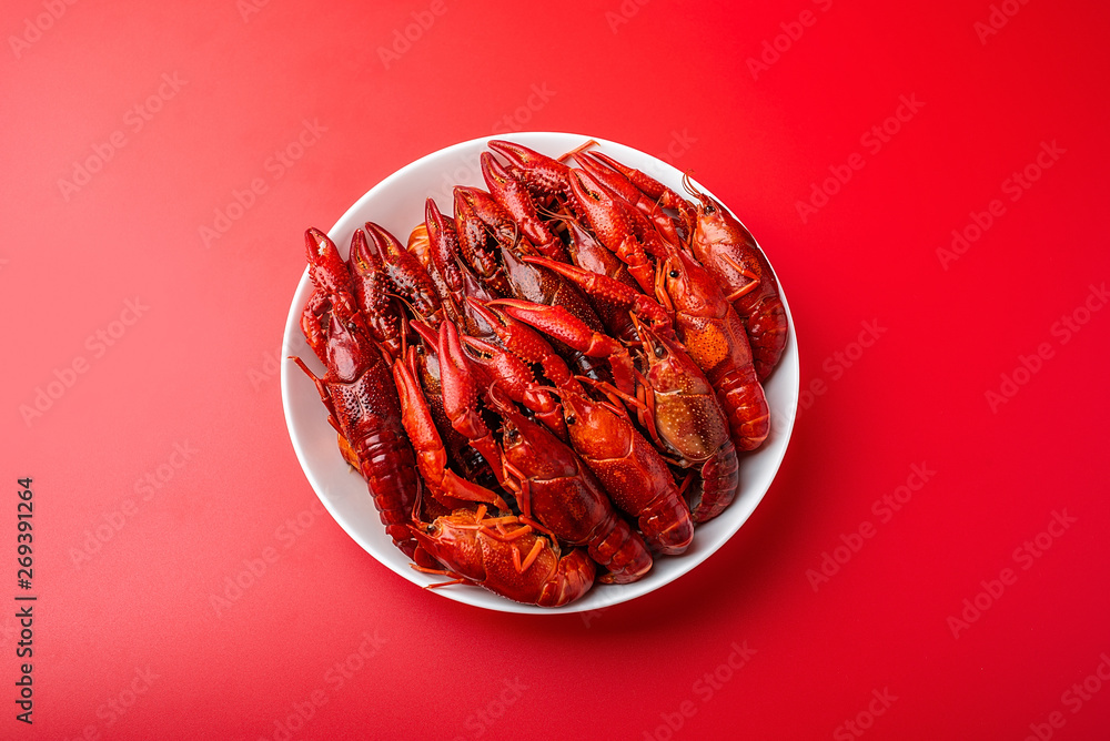 A large bowl of bright red delicious crayfish on a red background