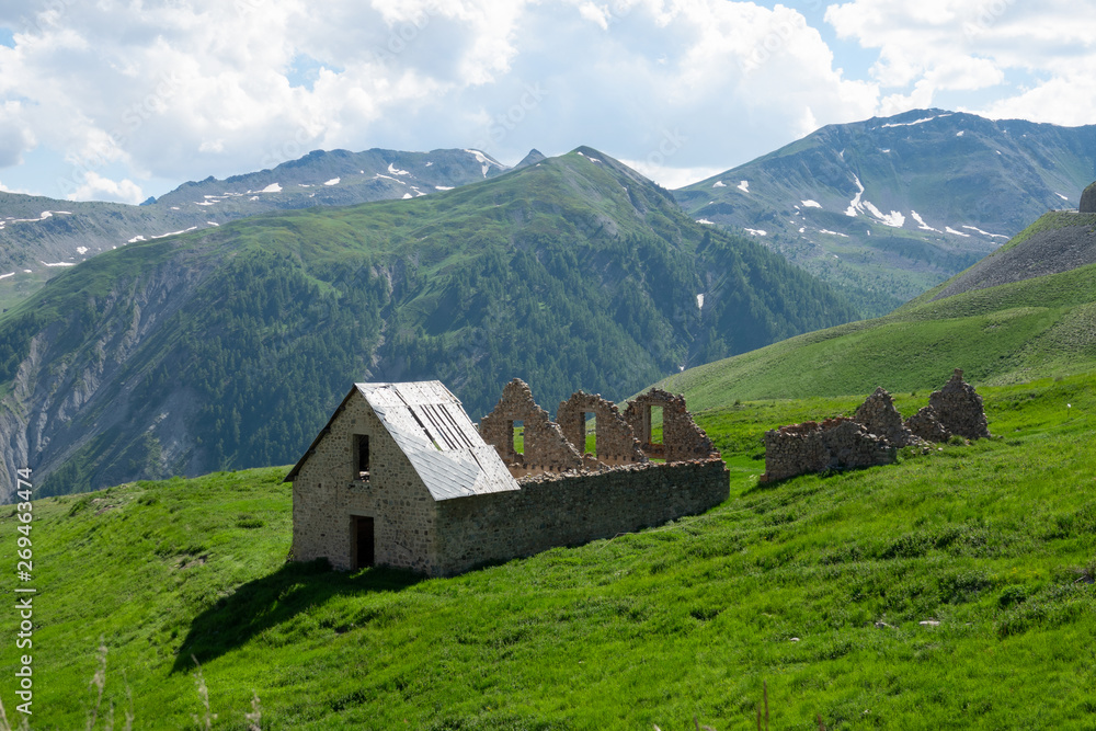 Old medieval country house decays in the middle of a vibrant green meadow.