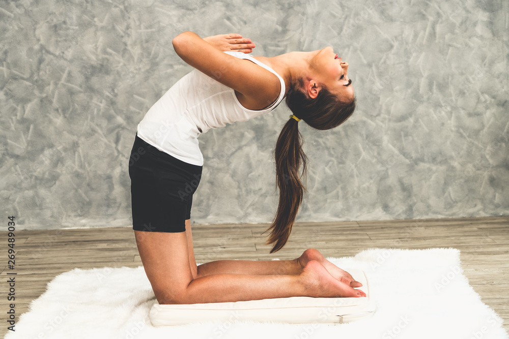 Young beautiful woman do yoga exercise on carpet at home living room. Healthy lifestyle and relaxati