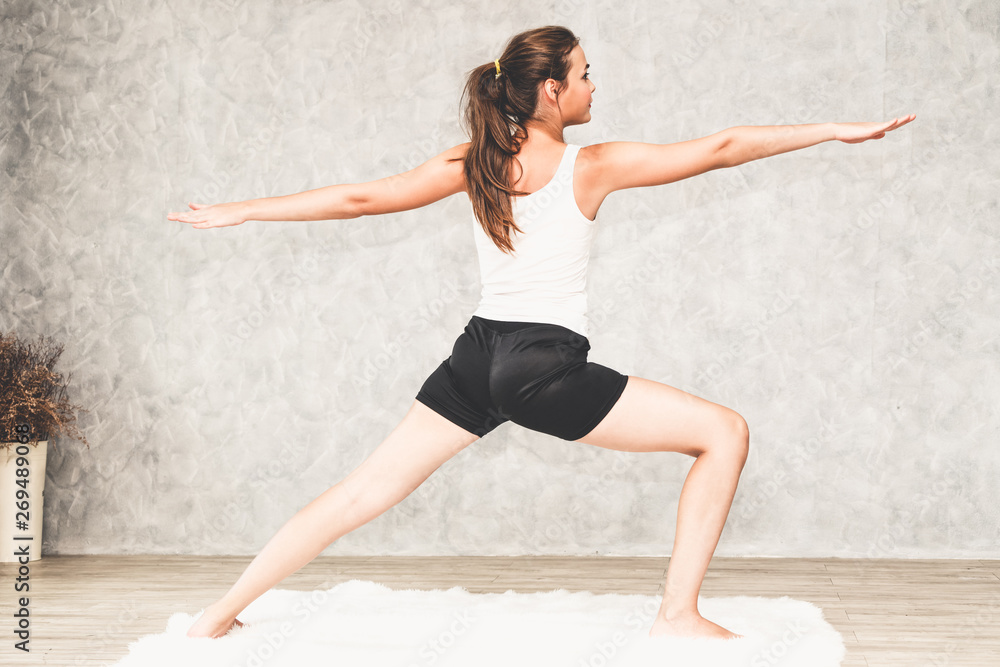 Young beautiful woman do yoga exercise on carpet at home living room. Healthy lifestyle and relaxati