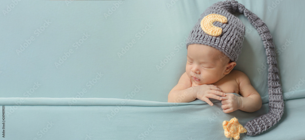 Adorable newborn baby sleeping in cozy room. Cute happy infant baby portrait with sleepy face in bed