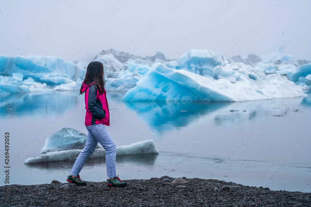 Woman traveler travels to Jokulsarlon beautiful glacial lagoon in Iceland. Jokulsarlon is a famous d