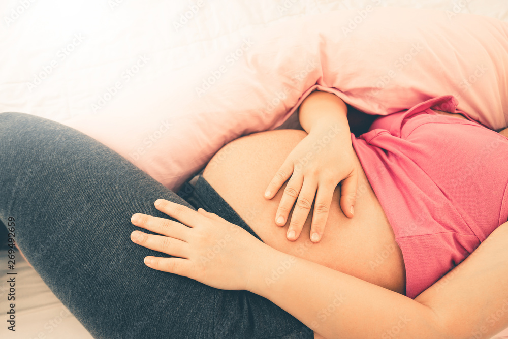 Happy pregnant woman sleeping on bed in bedroom at home for resting and stress relief. The young exp