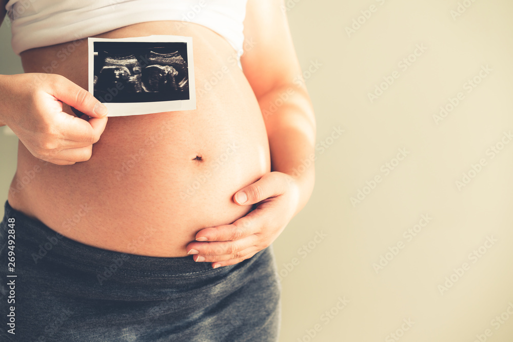 Pregnant woman feeling happy at home while taking care of her child. The young expecting mother hold