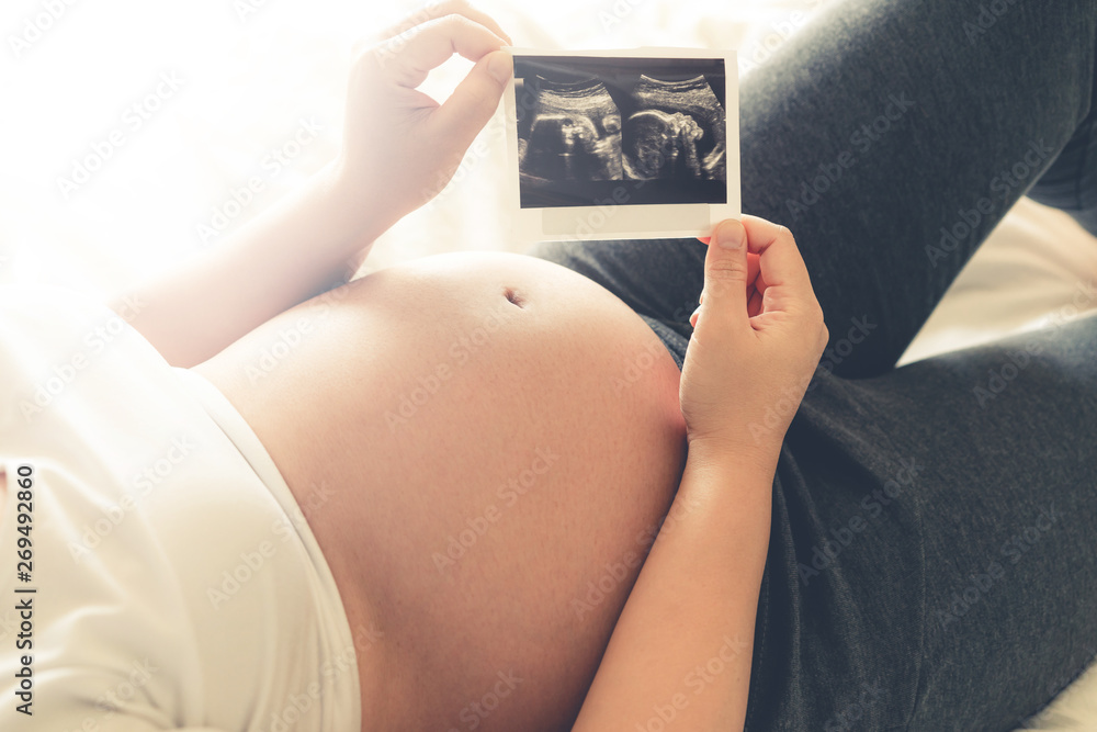 Pregnant woman feeling happy at home while taking care of her child. The young expecting mother hold