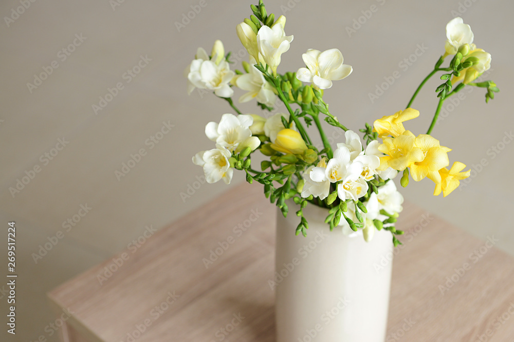 Vase with beautiful freesia flowers on table