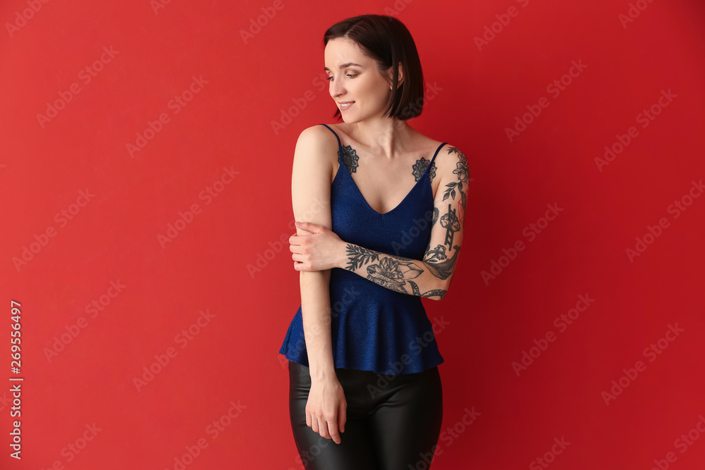 Beautiful tattooed woman on color background