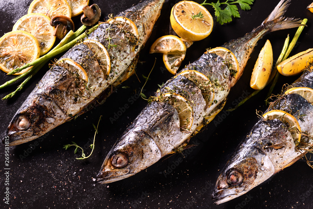 Grilled fish and various vegetables on iron plate background