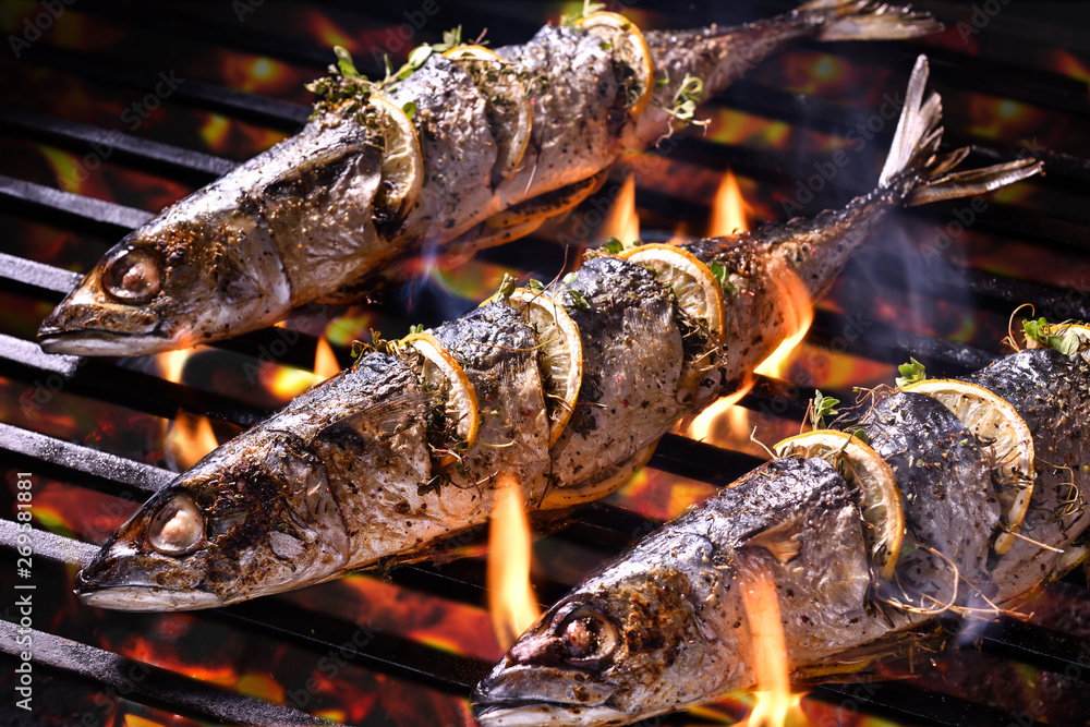 Grilled fish with slice lemons on the flaming grill