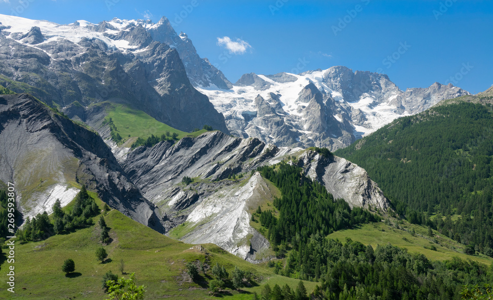 AERIAL: Flying across the vast green valley and towards spectacular glacier.