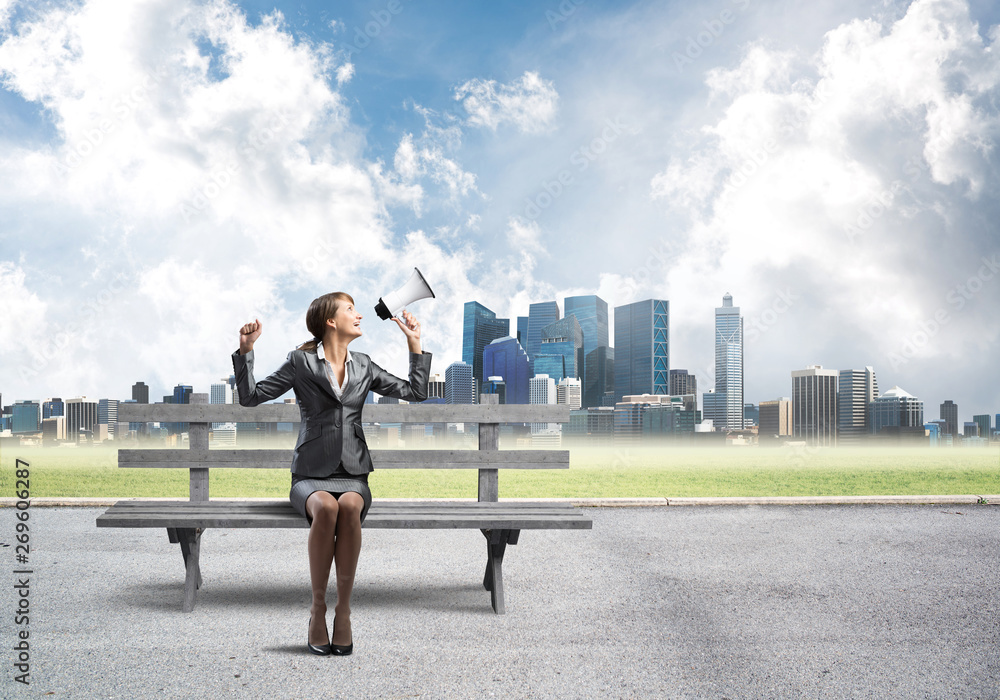 Business woman with megaphone on wooden bench