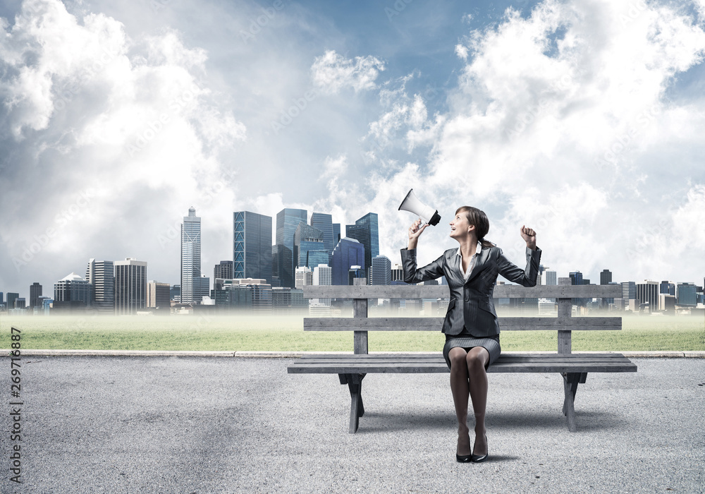 Business woman with megaphone on wooden bench