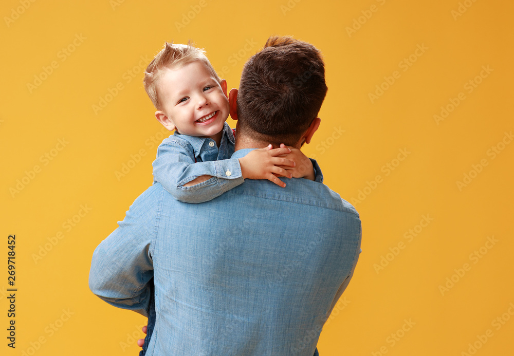 happy fathers day! cute dad and son hugging on yellow background.