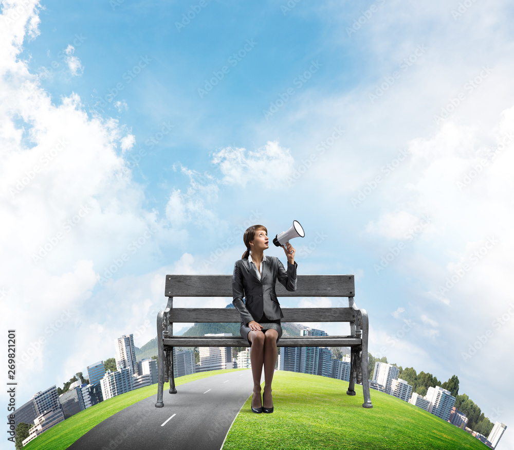 Business woman with megaphone on wooden bench