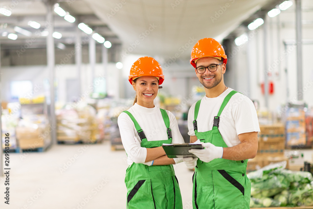 Portrait of a two happy quality control workers at food factory warehouse.