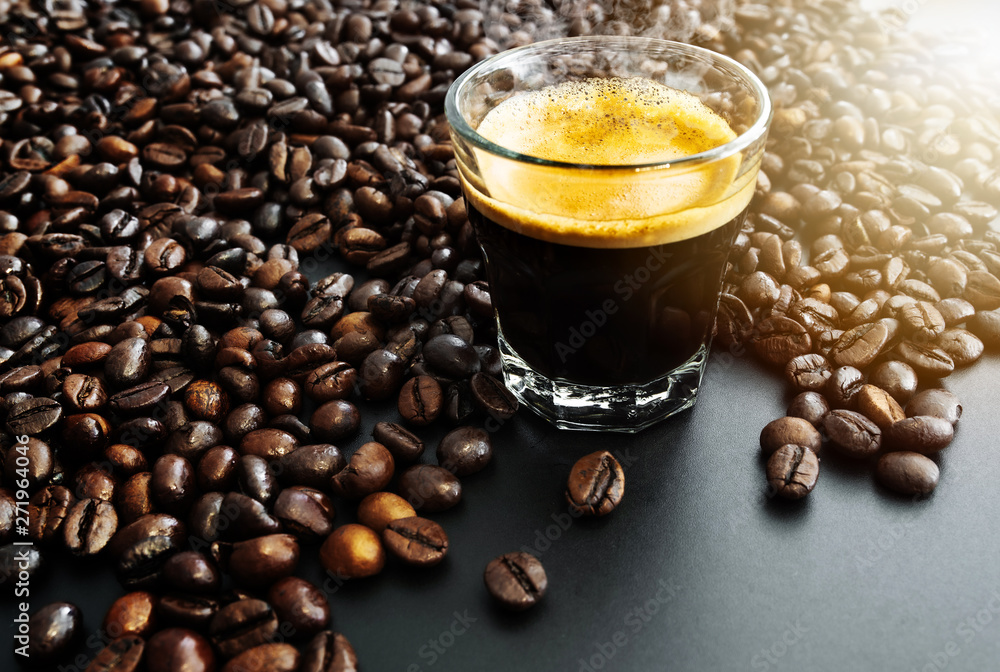 glass filled with dark  hot espresso coffee and roasted coffee beans on table