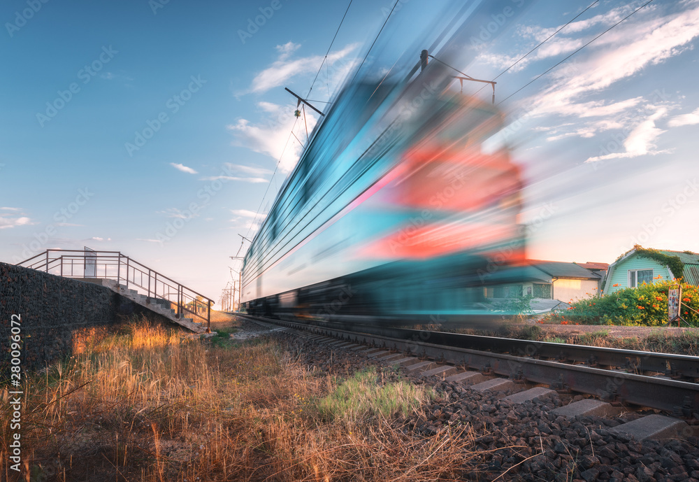 High speed passenger train in motion on the railroad at summer evening. Moving blurred modern commut