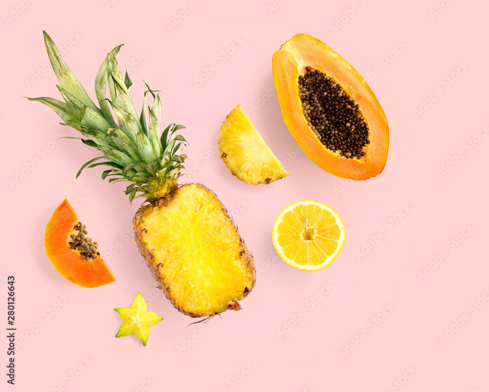 Creative layout made of pineapple, papaya, lemon, carambola on pink background.  Tropical flat lay. 