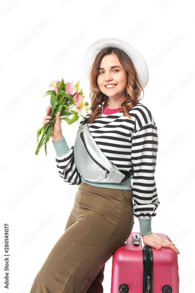 Female tourist with luggage and flowers on white background